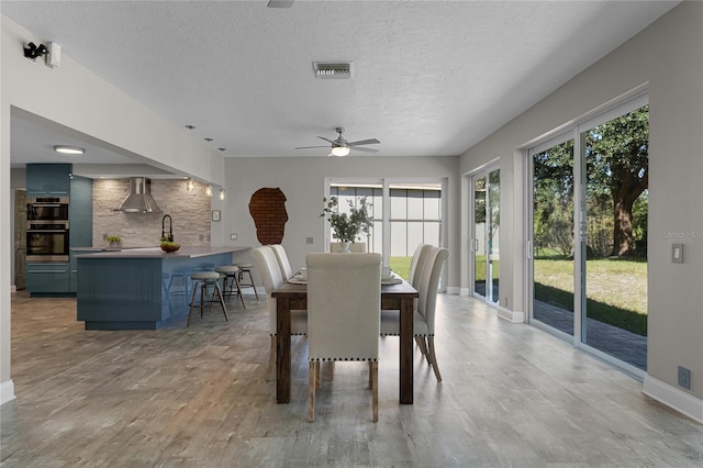 unfurnished dining area with ceiling fan, a textured ceiling, and hardwood / wood-style floors