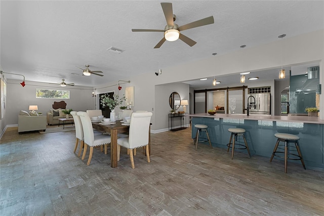 dining area with ceiling fan, wood-type flooring, and a textured ceiling