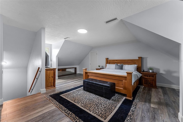 bedroom featuring dark wood-type flooring, a textured ceiling, and vaulted ceiling