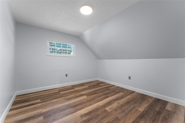 additional living space with a textured ceiling, lofted ceiling, and dark hardwood / wood-style floors