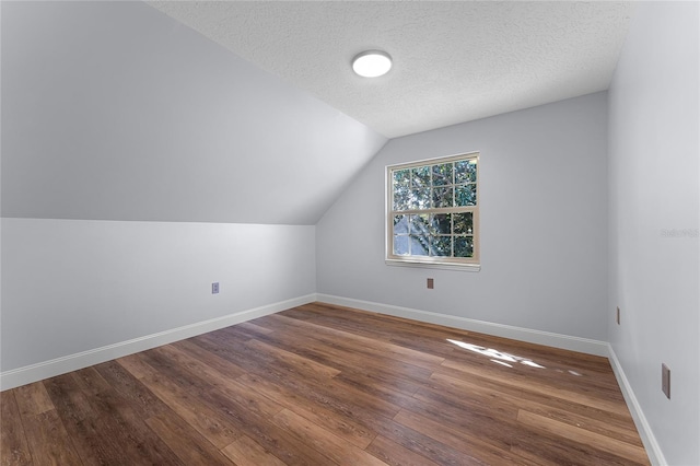 additional living space with a textured ceiling, hardwood / wood-style flooring, and vaulted ceiling