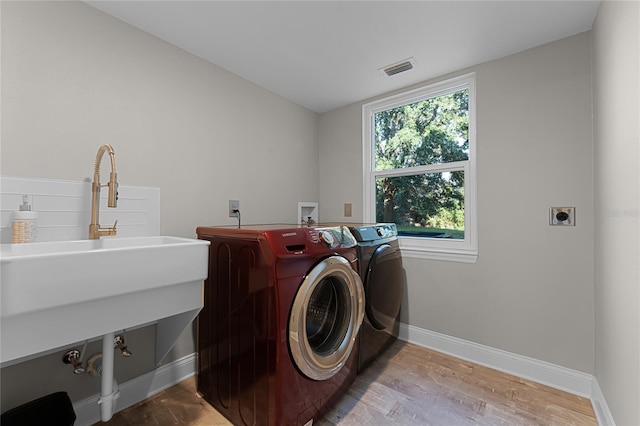 washroom with sink, washing machine and clothes dryer, and light hardwood / wood-style floors