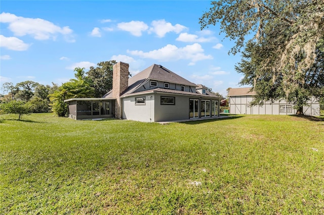 rear view of house featuring a lawn and a sunroom