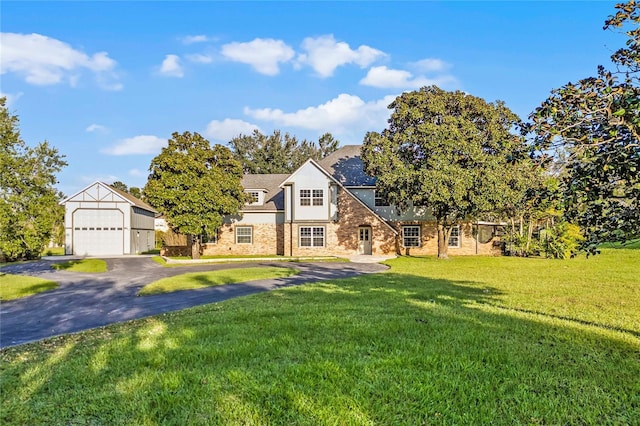 view of front of home featuring a front lawn, a detached garage, and brick siding