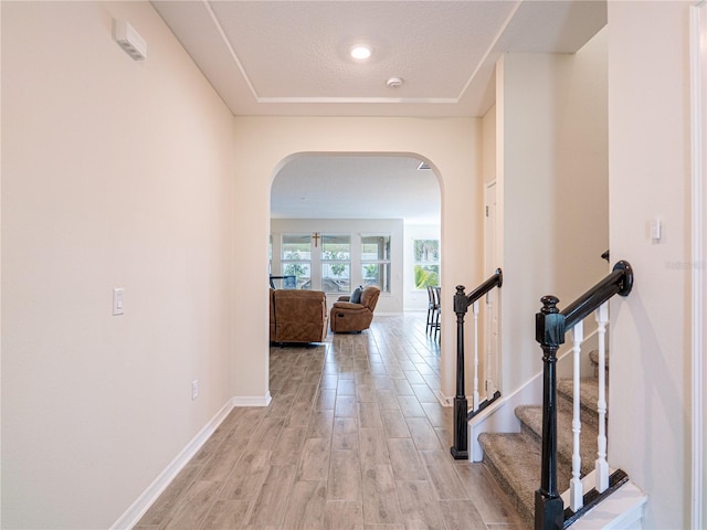 hall with light hardwood / wood-style floors and a textured ceiling