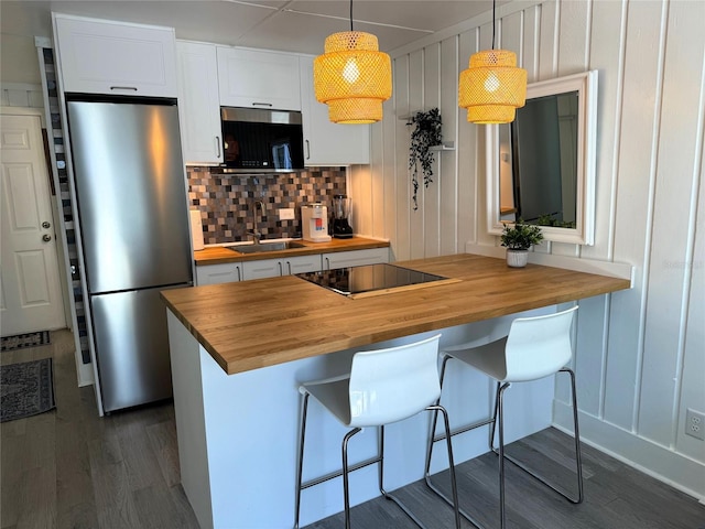 kitchen with a breakfast bar area, white cabinetry, pendant lighting, wooden counters, and stainless steel appliances