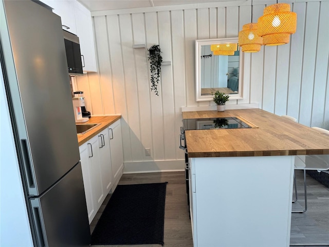 kitchen featuring butcher block counters, hanging light fixtures, stainless steel appliances, white cabinets, and dark hardwood / wood-style floors