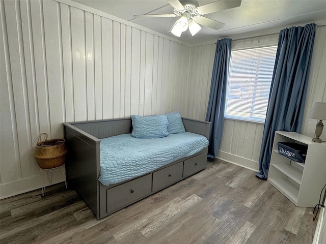 sitting room featuring hardwood / wood-style flooring, wooden walls, and ceiling fan