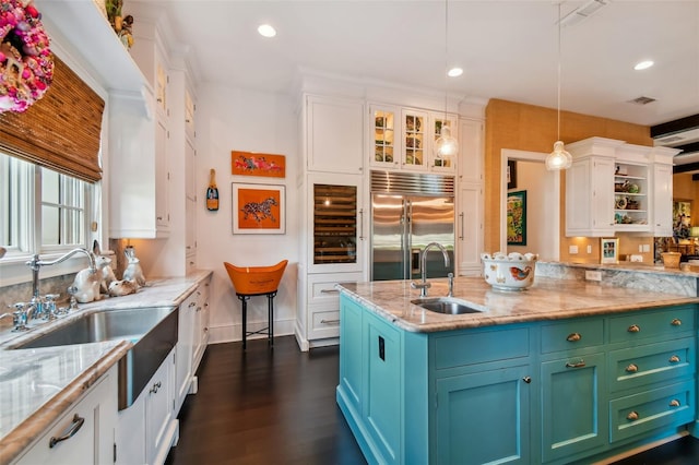 kitchen featuring sink, dark hardwood / wood-style flooring, hanging light fixtures, white cabinets, and stainless steel built in fridge