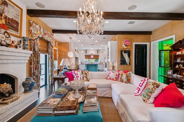 living room featuring beam ceiling, a notable chandelier, and a brick fireplace