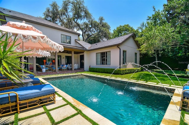 rear view of property with a patio, pool water feature, and a yard