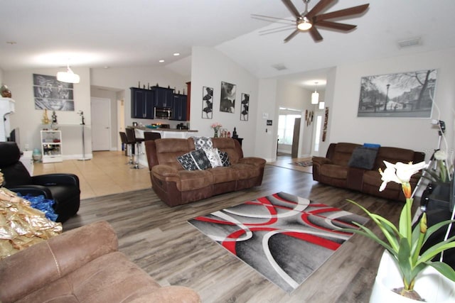 living room with ceiling fan, vaulted ceiling, and hardwood / wood-style floors