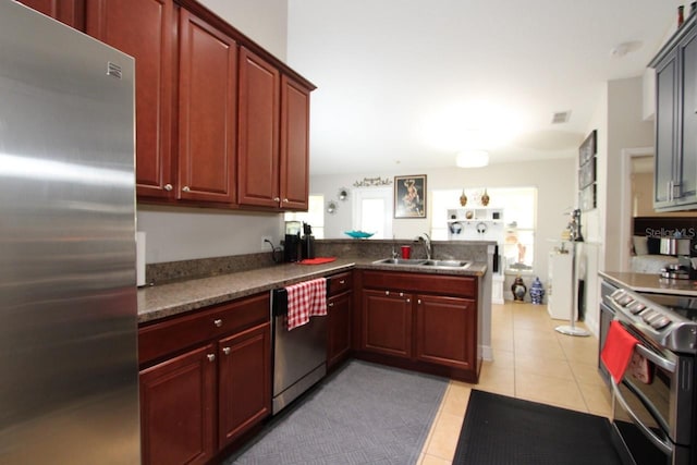 kitchen with light tile patterned flooring, appliances with stainless steel finishes, sink, and kitchen peninsula