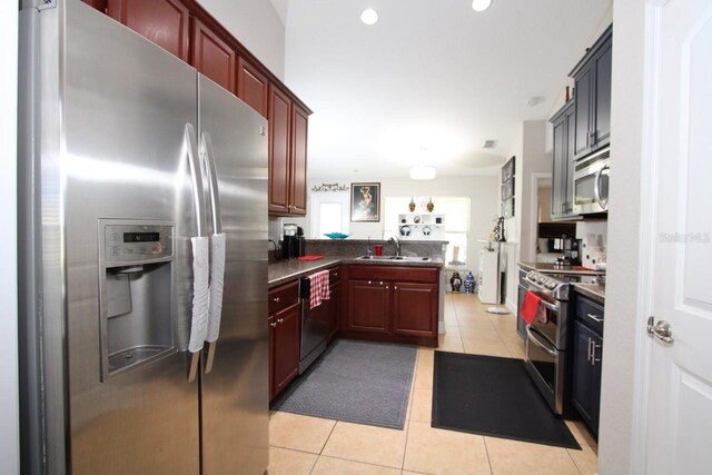 1545 Blue Sky Blvd, Haines City, FL 33844 - kitchen featuring stainless steel appliances, light tile patterned floors, dark countertops, a peninsula, and dark brown cabinets