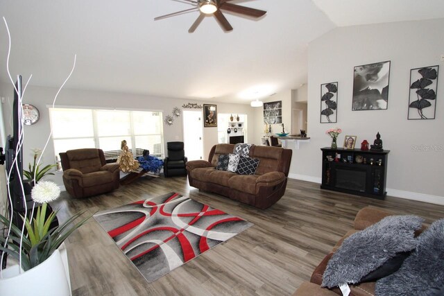 living room featuring ceiling fan, wood-type flooring, and vaulted ceiling