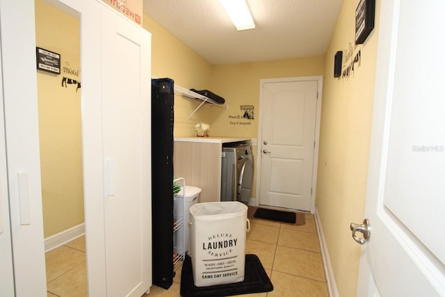 laundry room featuring washing machine and clothes dryer and light tile patterned floors