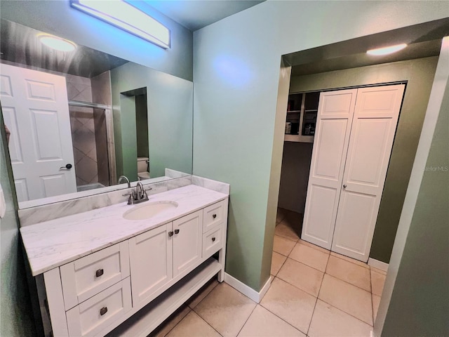 bathroom with toilet, vanity, tile patterned floors, and a shower with shower door