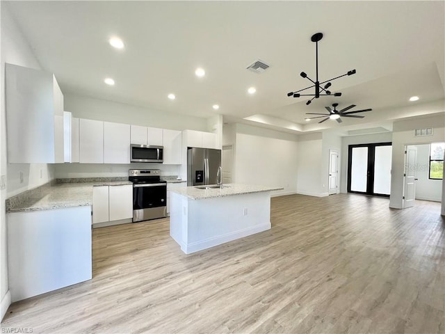 kitchen with white cabinetry, light hardwood / wood-style floors, stainless steel appliances, and a kitchen island