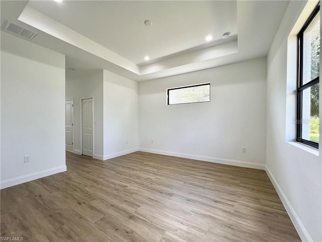 empty room featuring hardwood / wood-style flooring and a tray ceiling