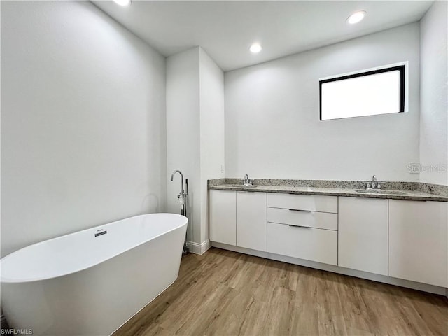 bathroom featuring vanity, a tub to relax in, and hardwood / wood-style floors