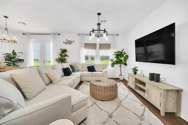 living room with an inviting chandelier, french doors, and wood-type flooring