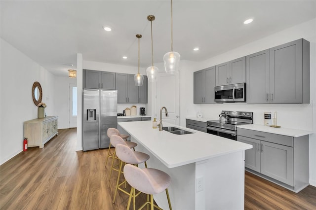 kitchen with appliances with stainless steel finishes, sink, gray cabinets, and dark hardwood / wood-style flooring