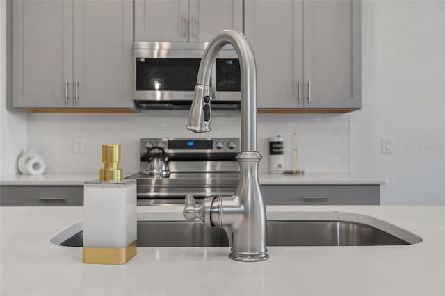 kitchen featuring gray cabinets, tasteful backsplash, and sink