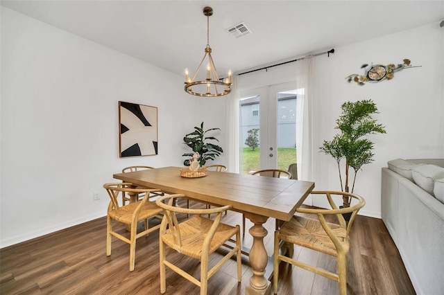 dining room with dark wood-type flooring, an inviting chandelier, and french doors