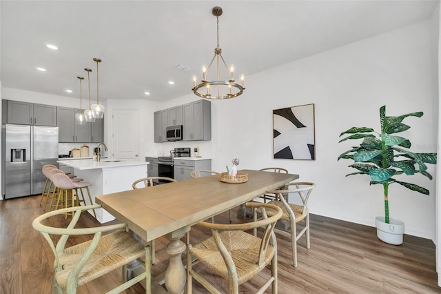 dining area with sink, hardwood / wood-style floors, and a notable chandelier