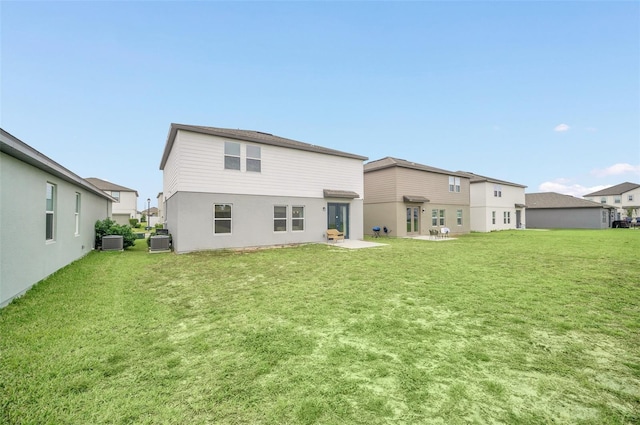 rear view of house featuring a patio, central AC, and a lawn