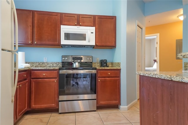 kitchen with light tile patterned floors, white appliances, and light stone counters