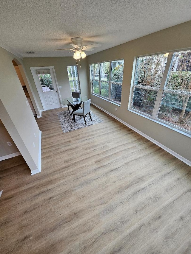 unfurnished sunroom with ceiling fan