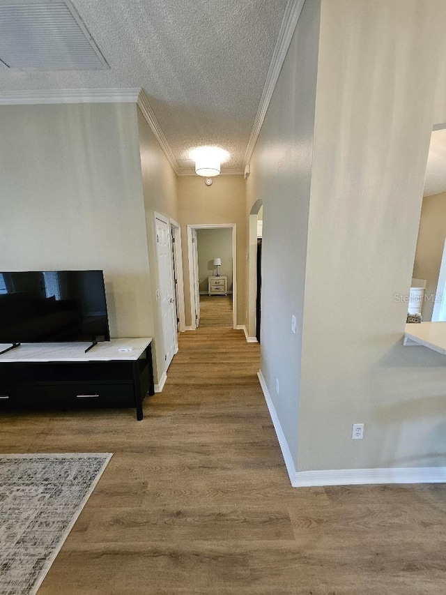 corridor with hardwood / wood-style flooring, a textured ceiling, and ornamental molding