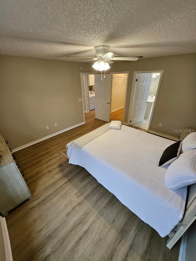 bedroom featuring a textured ceiling, hardwood / wood-style flooring, a spacious closet, and ceiling fan