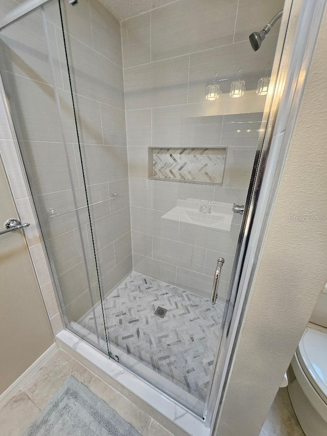 bathroom featuring tile patterned flooring, toilet, and walk in shower