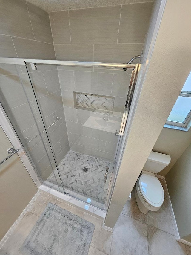 bathroom featuring tile patterned flooring, toilet, and an enclosed shower