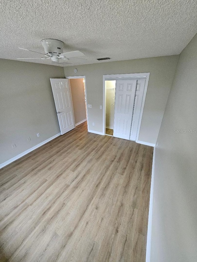 unfurnished bedroom featuring ceiling fan, light hardwood / wood-style floors, a textured ceiling, and a closet