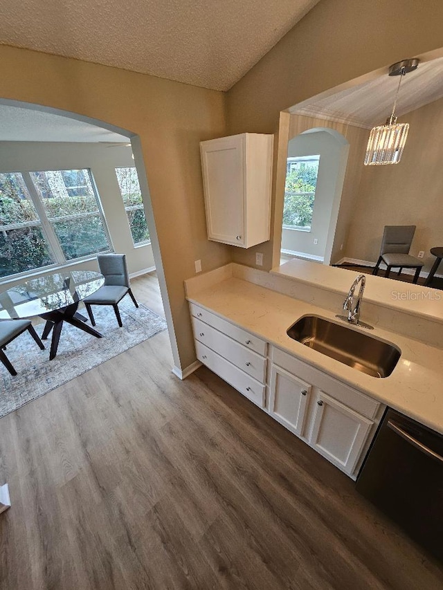 kitchen with stainless steel dishwasher, a textured ceiling, sink, decorative light fixtures, and white cabinets