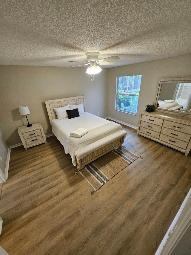 bedroom with dark hardwood / wood-style flooring, a textured ceiling, and ceiling fan