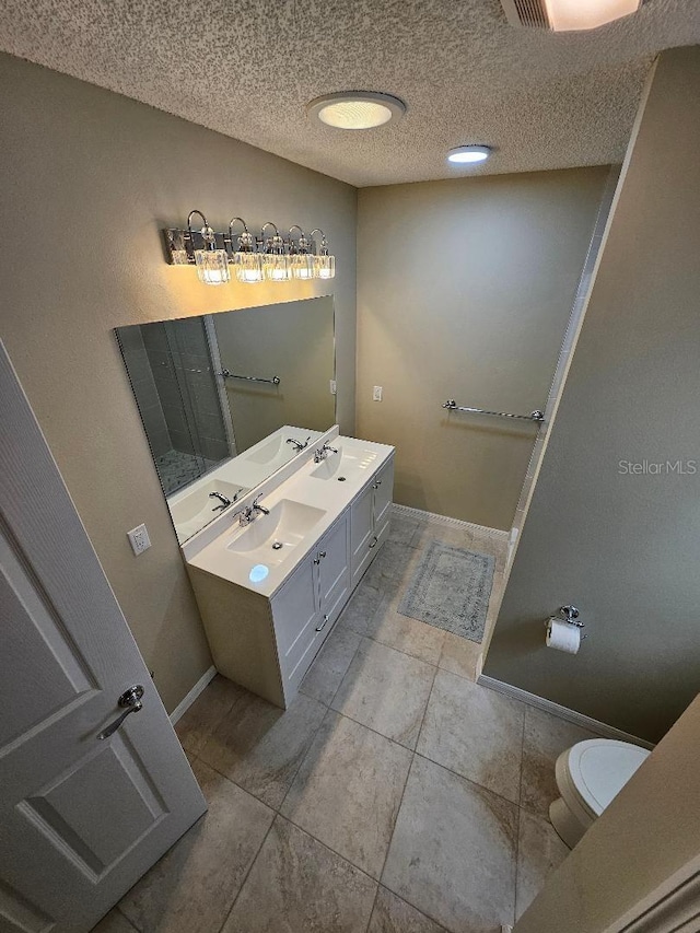 bathroom with vanity, a textured ceiling, toilet, and tile patterned flooring