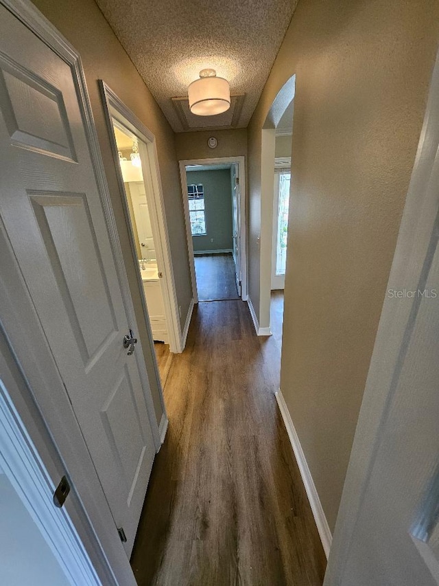 hall featuring a textured ceiling and dark wood-type flooring