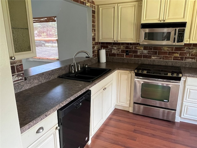 kitchen with appliances with stainless steel finishes, dark hardwood / wood-style floors, tasteful backsplash, and sink