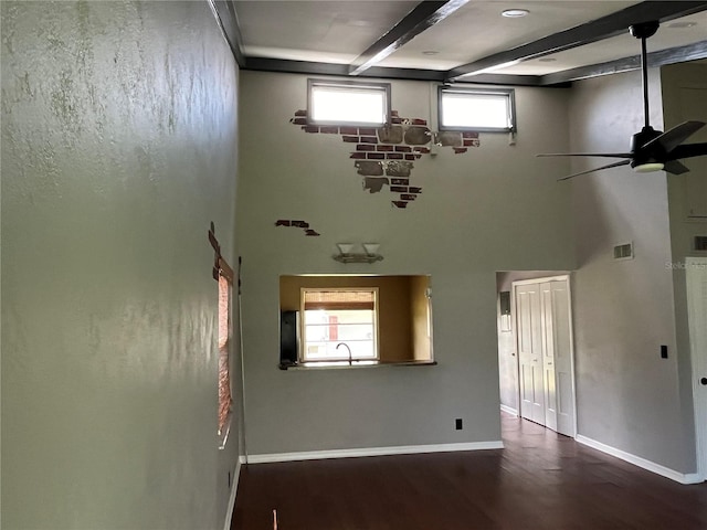 interior space with dark wood-type flooring, ceiling fan, beamed ceiling, and plenty of natural light