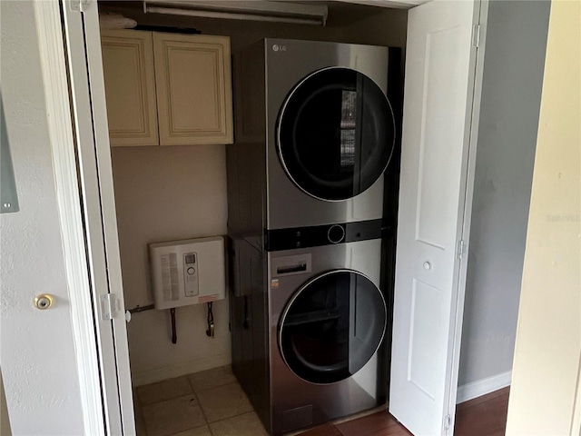 laundry room featuring cabinets, stacked washer and dryer, and tile patterned floors