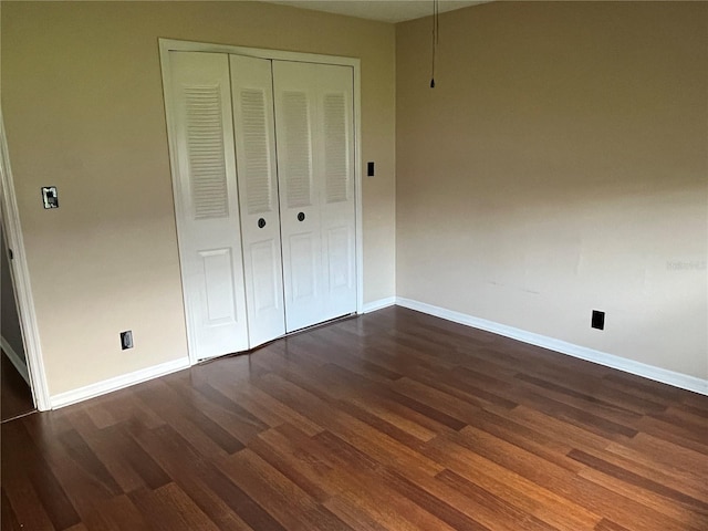 unfurnished bedroom featuring a closet and dark hardwood / wood-style flooring