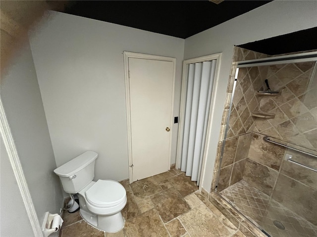 bathroom featuring toilet and a shower with shower door