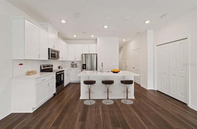 kitchen with a center island with sink, appliances with stainless steel finishes, dark hardwood / wood-style floors, and white cabinetry