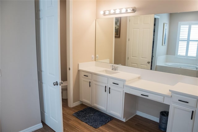 bathroom with vanity, toilet, a tub, and hardwood / wood-style floors