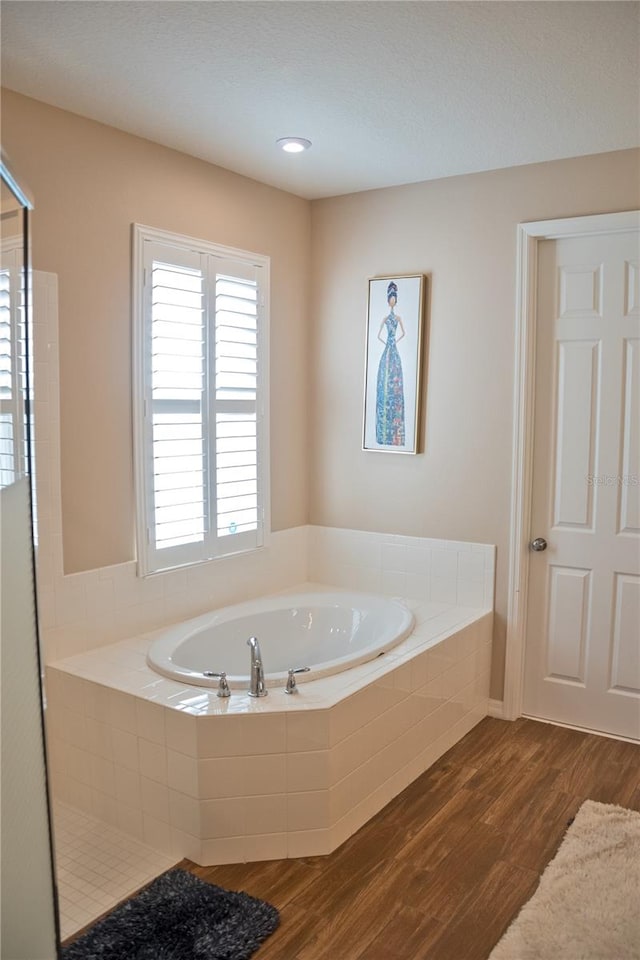 bathroom featuring a relaxing tiled tub and hardwood / wood-style flooring