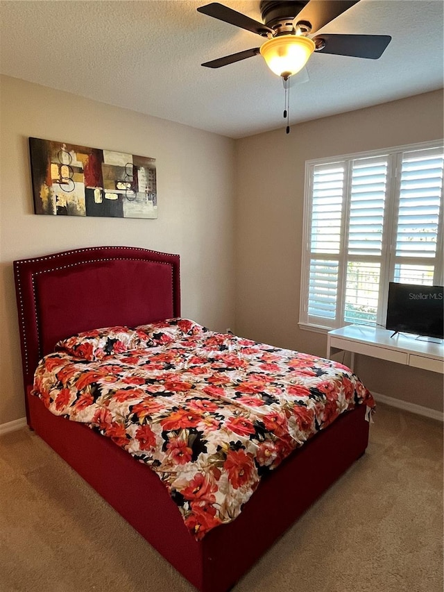 bedroom with ceiling fan, carpet flooring, and a textured ceiling